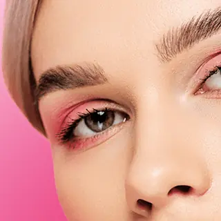 Close-up of a freshly waxed, shaped brow above pink eyeshadow
